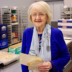 Rosemary Kowalski holding some of her favorite recipes from her collection, including one for chocolate pudding.